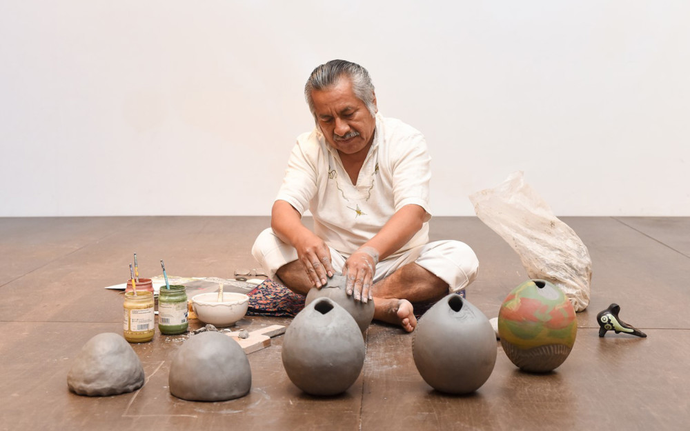 artist siting with pottery he created