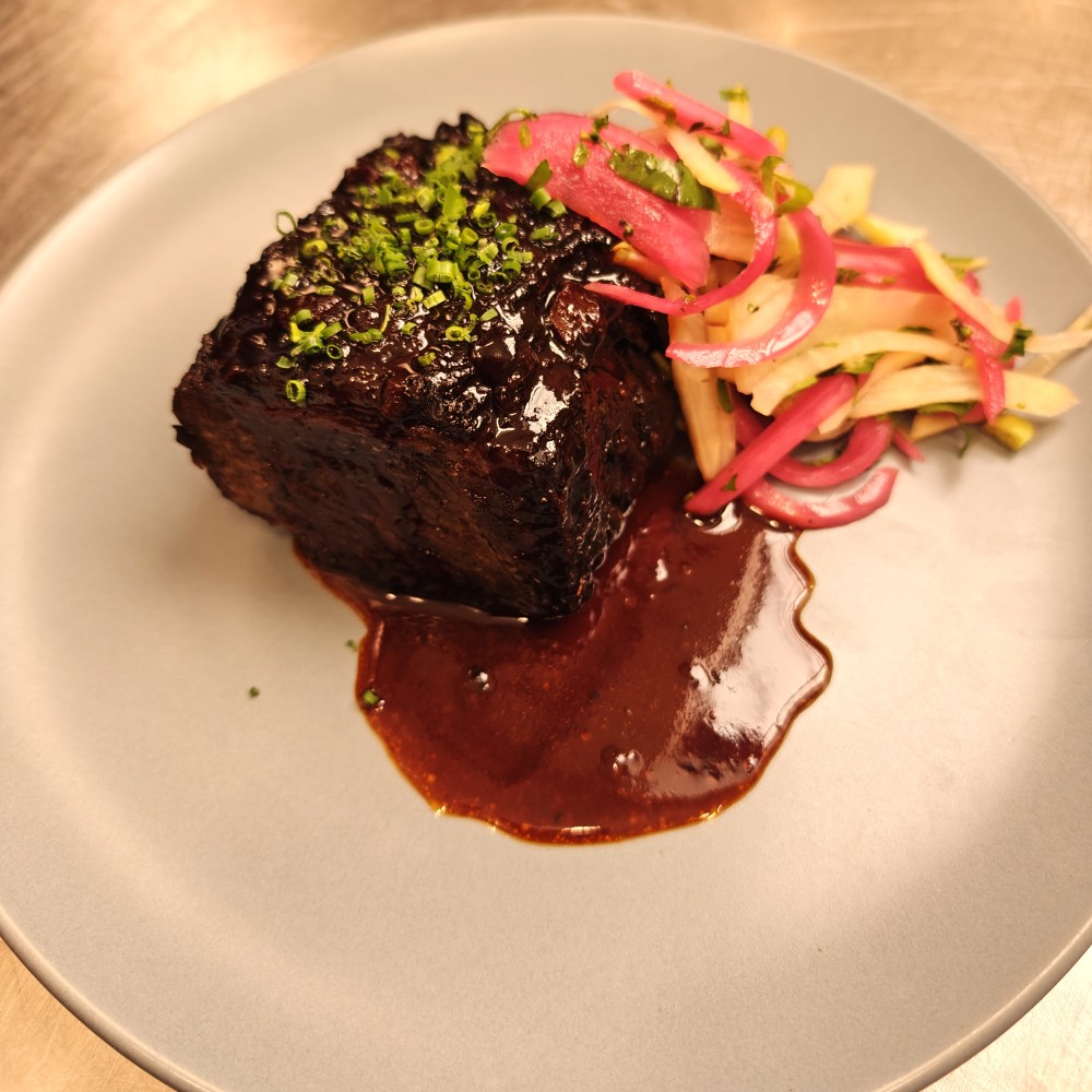 Costilla corta deshuesada y cocida a fuego lento, reducción de gochujang demi, ensalada de pepinillos