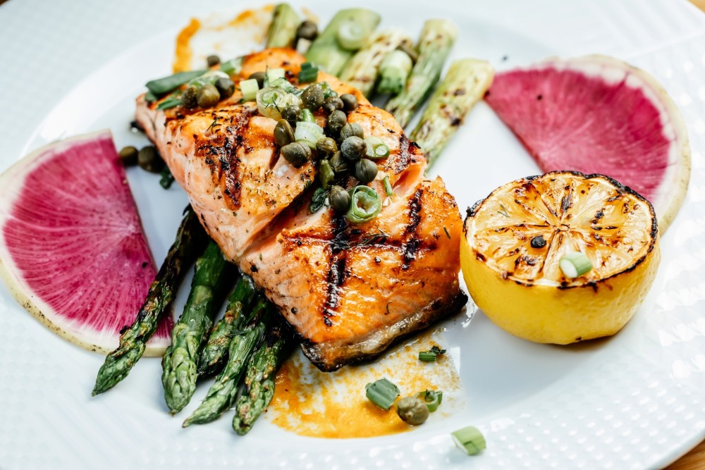 Faroe Island salmon fillet with scallions, capers, and lemon sauce with grilled asparagus.