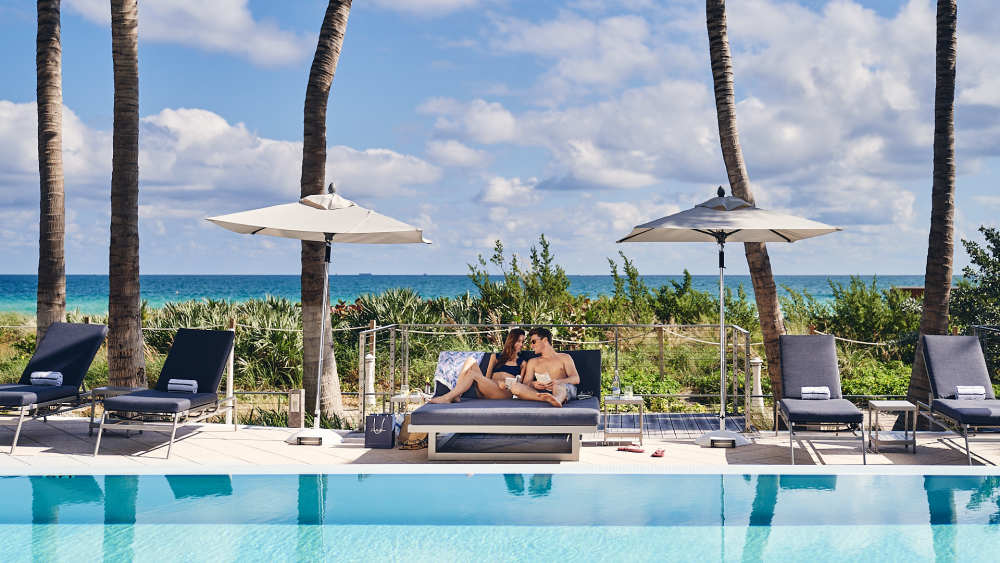 Um casal relaxando à beira da piscina no Carillon Miami Wellness Resort.