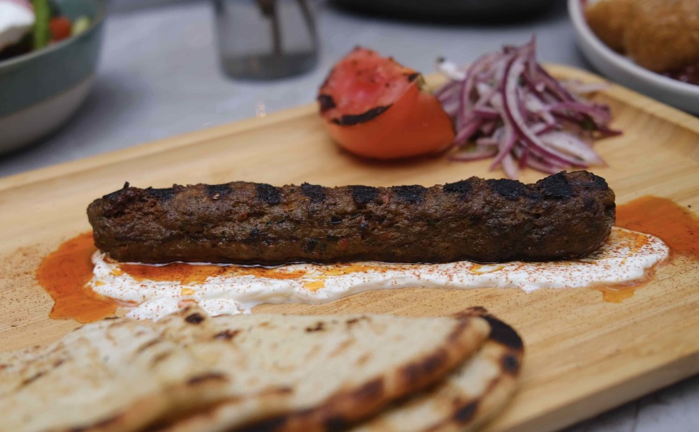 Kebab grego com cordeiro e carne moída, cebola sumagre, tomate grelhado, molho de iogurte, páprica doce