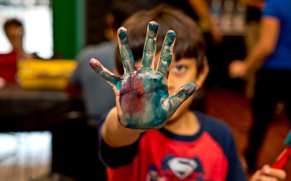 Kind mit Farbe an der Hand