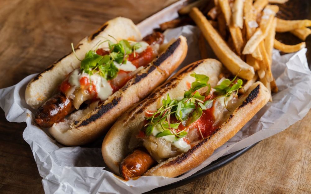 尽情享用我们的 Hot Dog de Txistorra，这是一种令人垂涎欲滴的巴斯克美食，以香肠为特色，佐以番茄酱、焦糖洋葱、胡椒酱和自制薯条，为您提供令人愉悦的美味 Fusion 口味和质地。