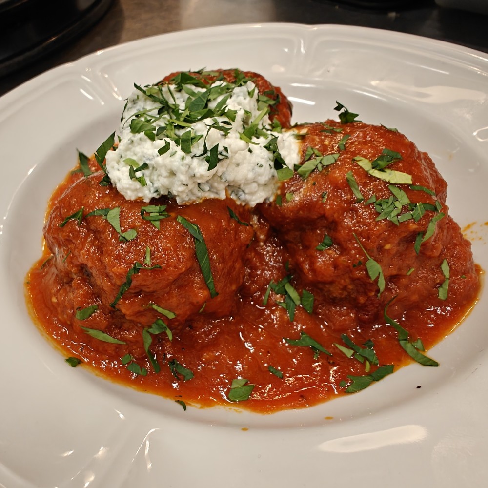 Boulèt vyann kochon ak vyann bèf, kwit nan yon sòs marinara, anlè kay fè fwete zèb ricotta, farinen ak Extra Virgin lwil oliv.