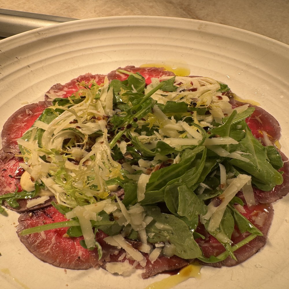 Carpaccio de ternera, tapenade de aceitunas, ensalada de rúcula, queso parmesano.