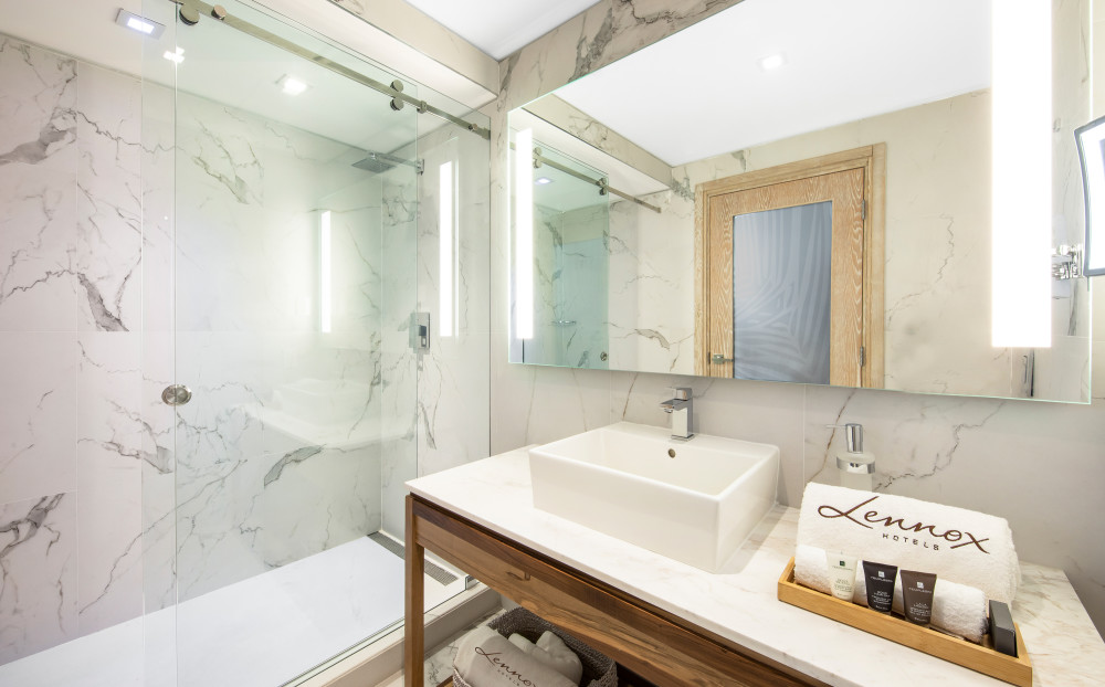 Banho e cuidados pessoais • Espelho principal do banheiro com luz natural integrada • Espelho de maquiagem com luz • Artigos de toalete vegan premium • Cofre no quarto