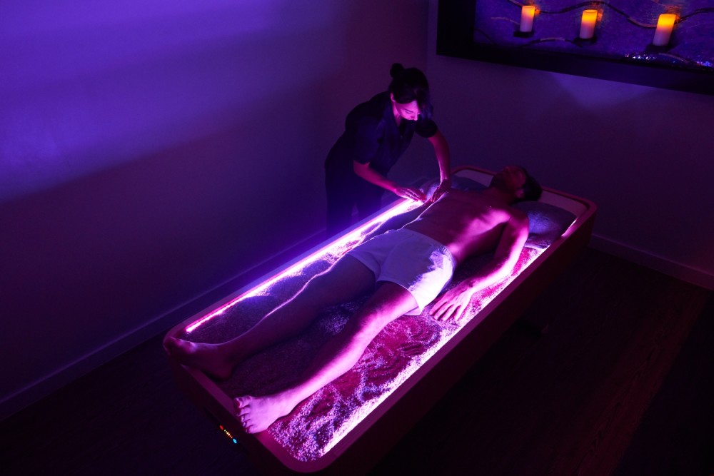 Un massaggio equilibrante al quarzo è rappresentato su un lettino da massaggio in cristallo di quarzo di Lemi.
