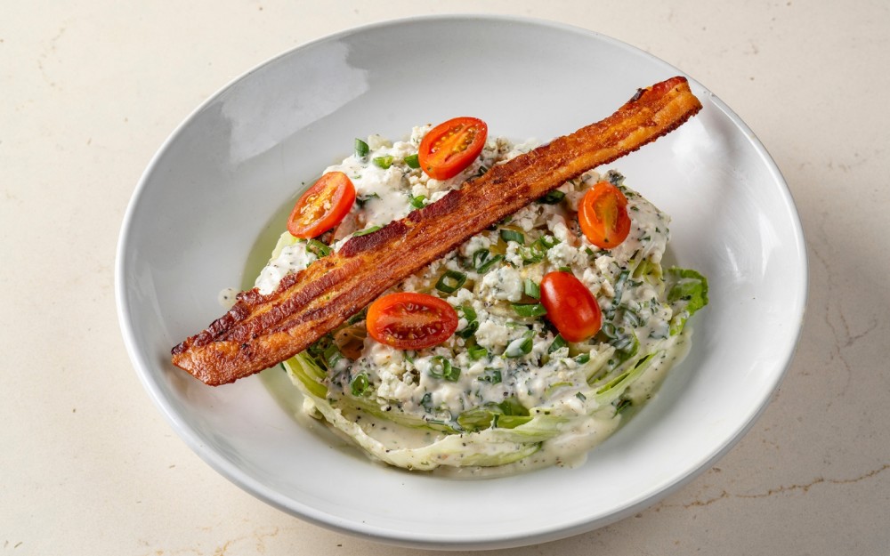 Wedge of crisp Iceberg lettuce, topped with our house buttermilk vinaigrette, grape tomatoes, chopped green onions and bacon