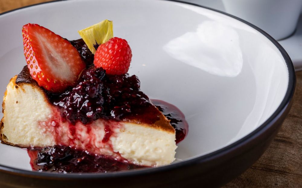 A nossa Tarta de Queso é um cheesecake basco com frutos silvestres, que oferece um equilíbrio perfeito entre sabores cremosos e frutados em cada mordida.