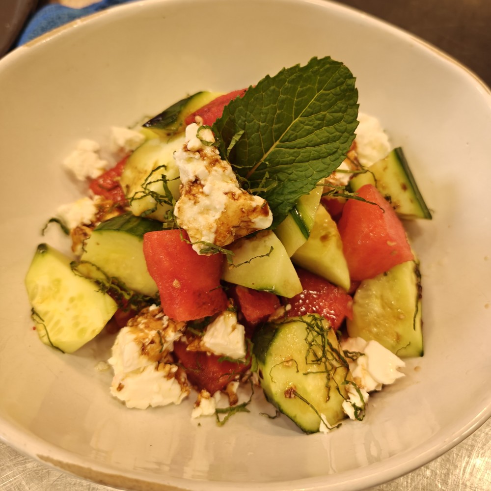 Fresh salada de melancia, pepino europeu e queijo feta, temperada com vinagrete balsâmico branco e finalizada com esmalte balsâmico envelhecido.