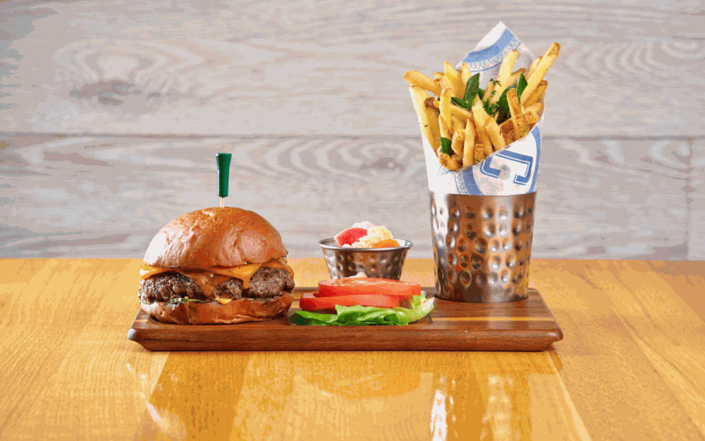 Libérez la saveur avec le Corsair Cheeseburger : Mélange 8oz, cornichon à l'ail, aïoli épicé, cheddar, frites aux herbes.