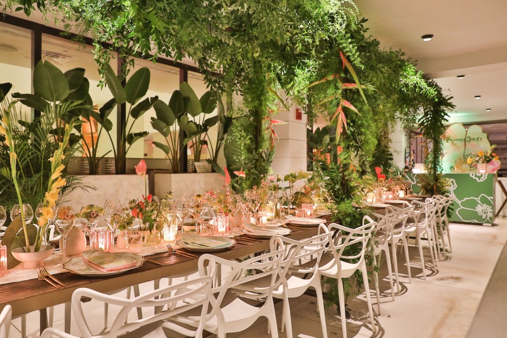 A lush hanging greenery canopy over a long dinner table, designed by oliFLOR for Perrier-Jouët in Miami.