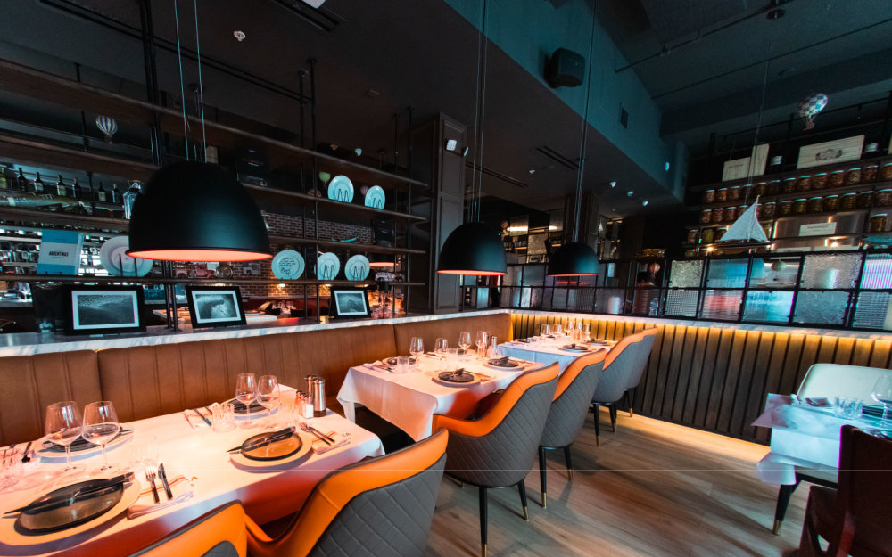 The interior merges modern warmth with Argentine flair—featuring plush banquette seating, rich leather tones, and dim inviting lightning.