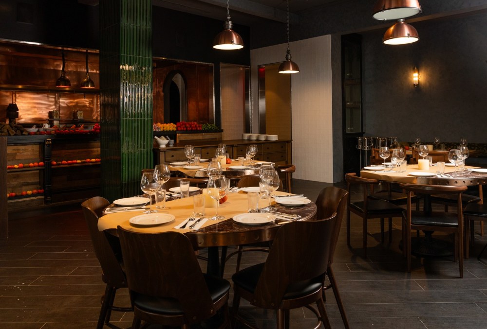 A lively, industrial-chic space with a dramatic overhead light installation, an ornate patinated bar and an open
produce market display
