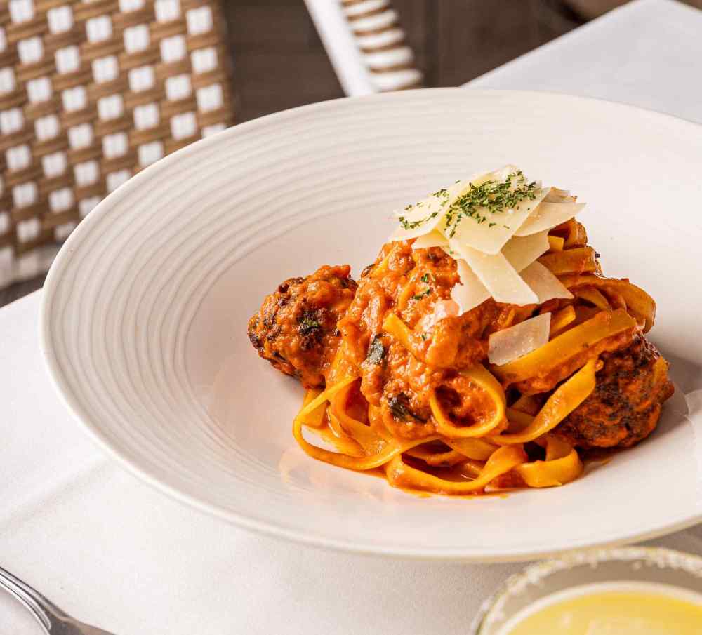 Hearty fettuccine with meatballs, rich tomato sauce, shaved Parmesan, and fresh herbs—comfort food with a Miami twist.
