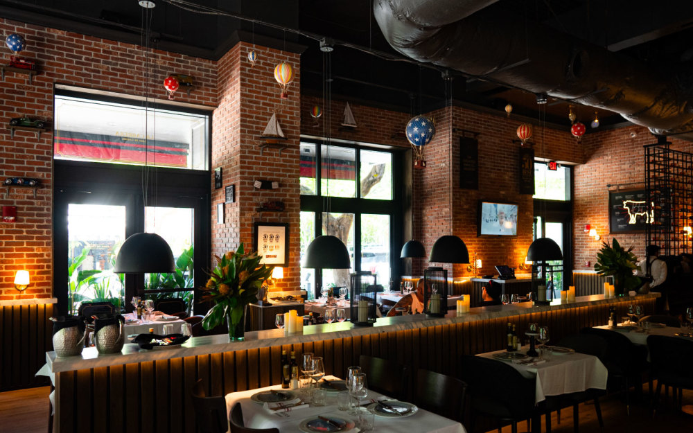 The interior merges modern warmth with Argentine flair featuring plush banquette seating, rich leather tones, and dim inviting lighting