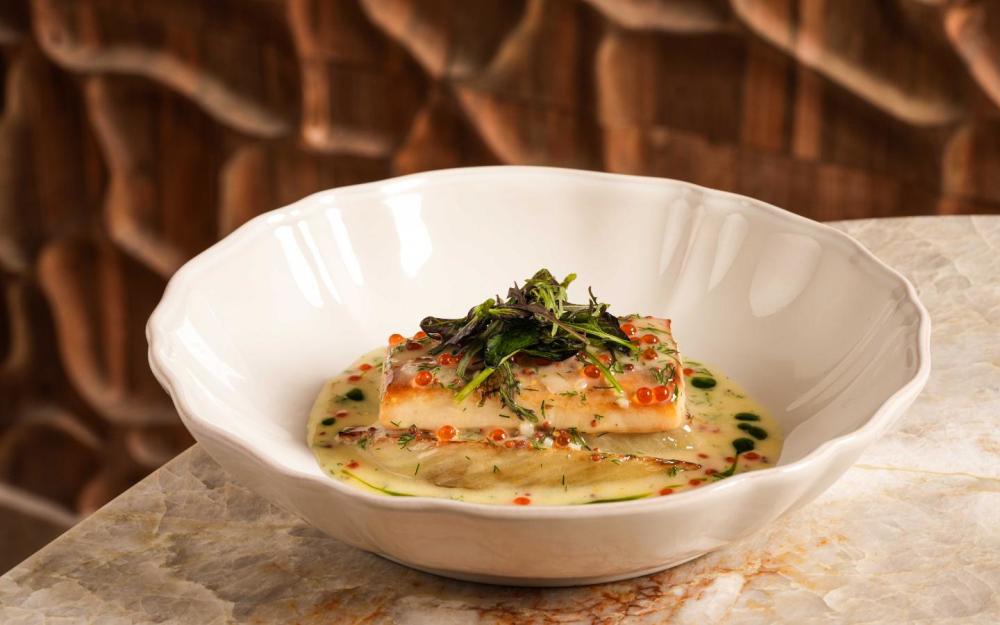 Pan-seared cobia in a citrus beurre blanc, topped with salmon roe and crisp herbs—Mediterranean indulgence redefined