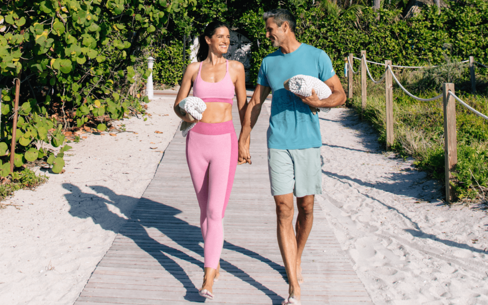 A couple enjoys a barefoot stroll along the sandy boardwalk, embracing nature and relaxation at The Palms Hotel & Spa.