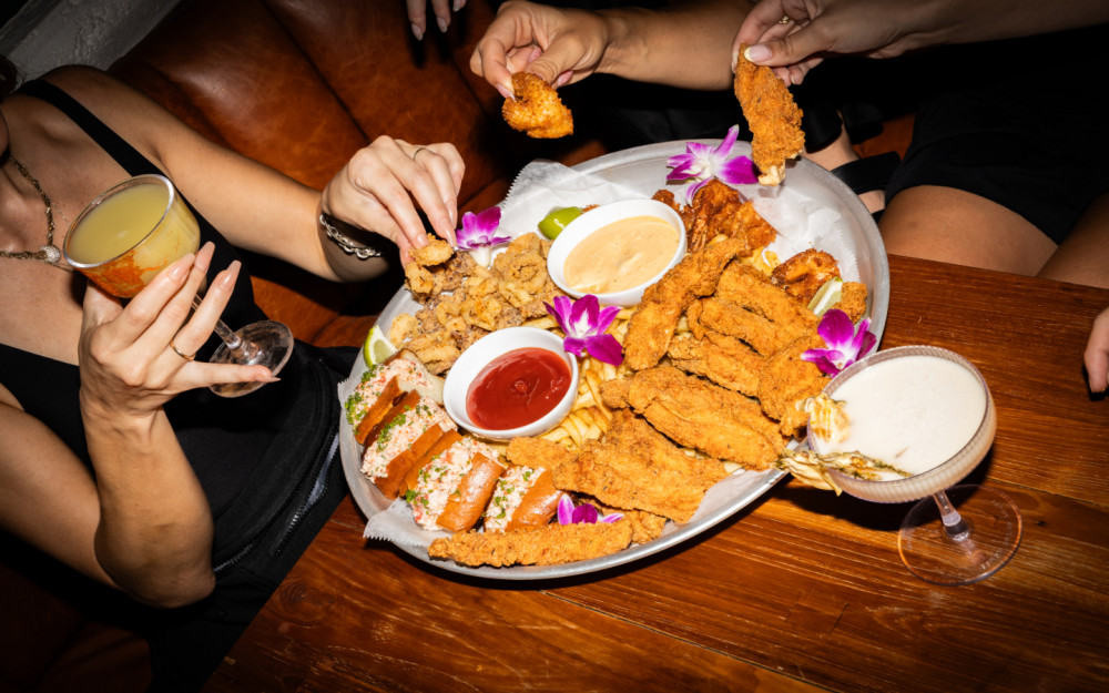Pass the platter, pour the drinks—chicken fingers, lobster sliders, and good company make every bite better at Palm Tree Club. Who’s joining in?