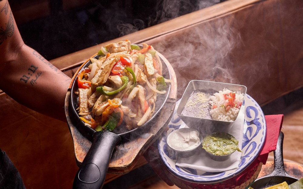Fajitas de frango, feijão preto refrito, arroz branco, guacamole, creme de leite e tortilhas quentes.