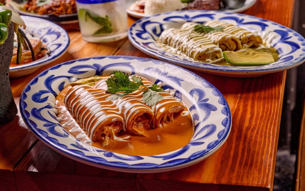Tortilhas de milho macias recheadas com frango ou queijo, cobertas com molho de tomate verde ou molho de pimenta guajillo vermelha, à sua escolha.