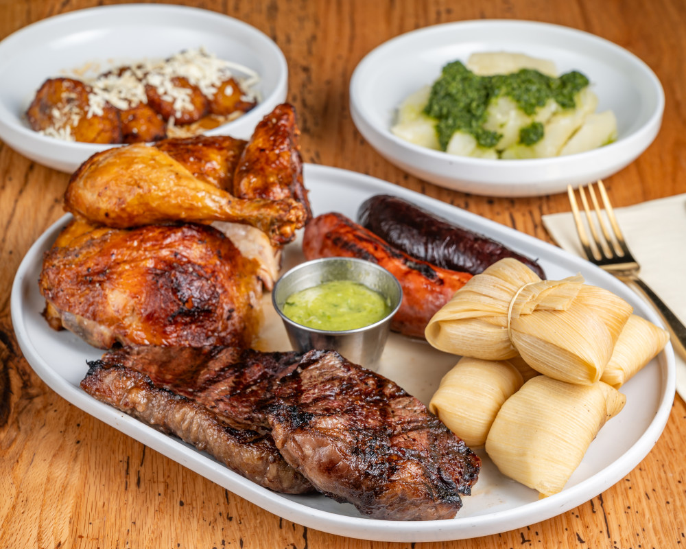 Latin-style mixed grill with picanha, rotisserie chicken, sausages, hallaquitas, yuca, and plantains