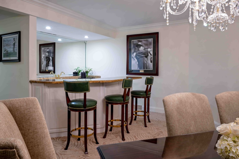 Spacious 1,295 sq. ft. Premier One-Bedroom Suite with king bed, separate living and dining areas, wet bar, marble baths, and garden or golf views.