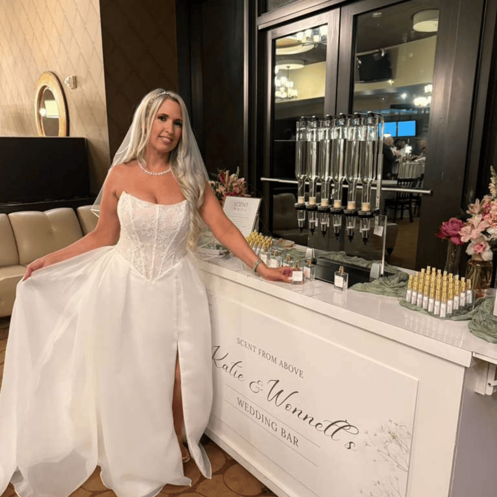 Bride posing next to a custom perfume bar at her wedding reception.