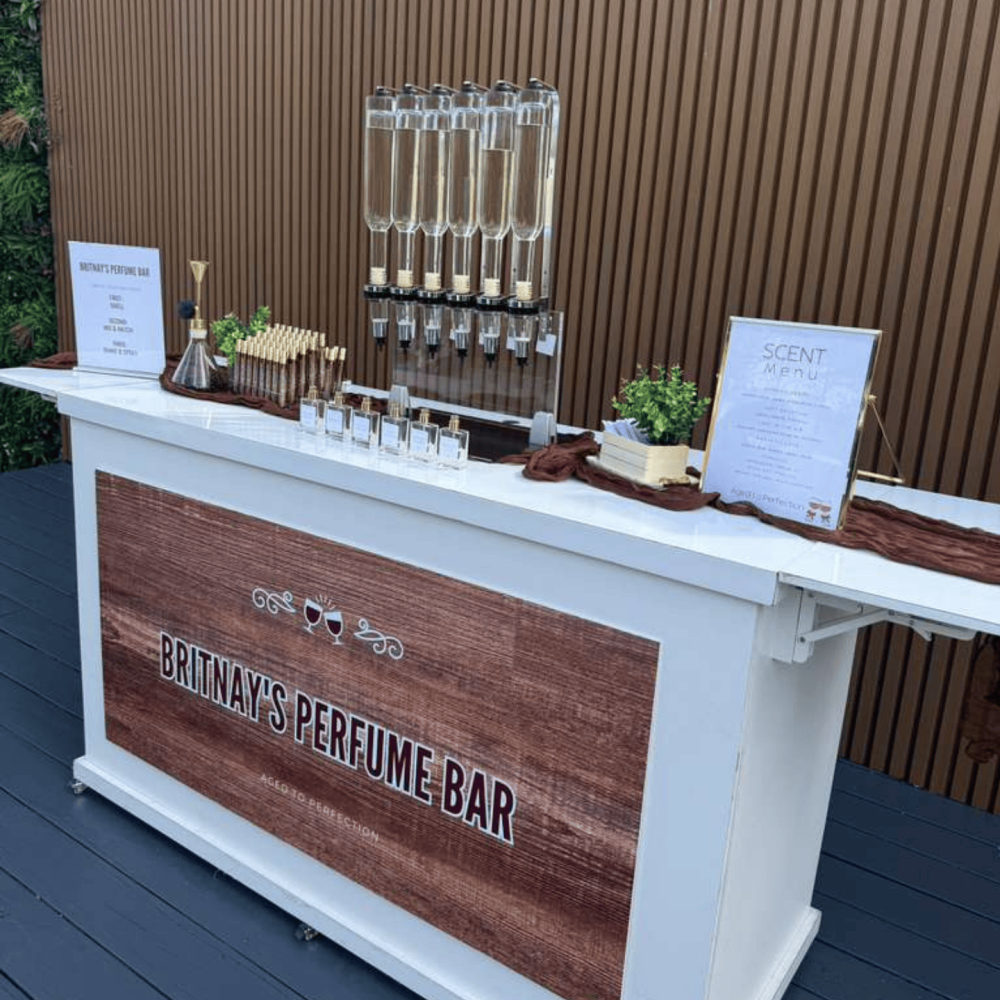 Outdoor perfume bar with wood accent signage and perfume bottles.