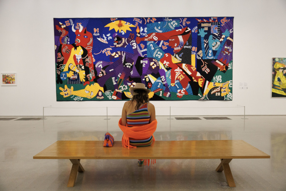 A woman sitting in front of "Guernica" by Hank Willis Thomas. Photo by WorldRedEye.com.