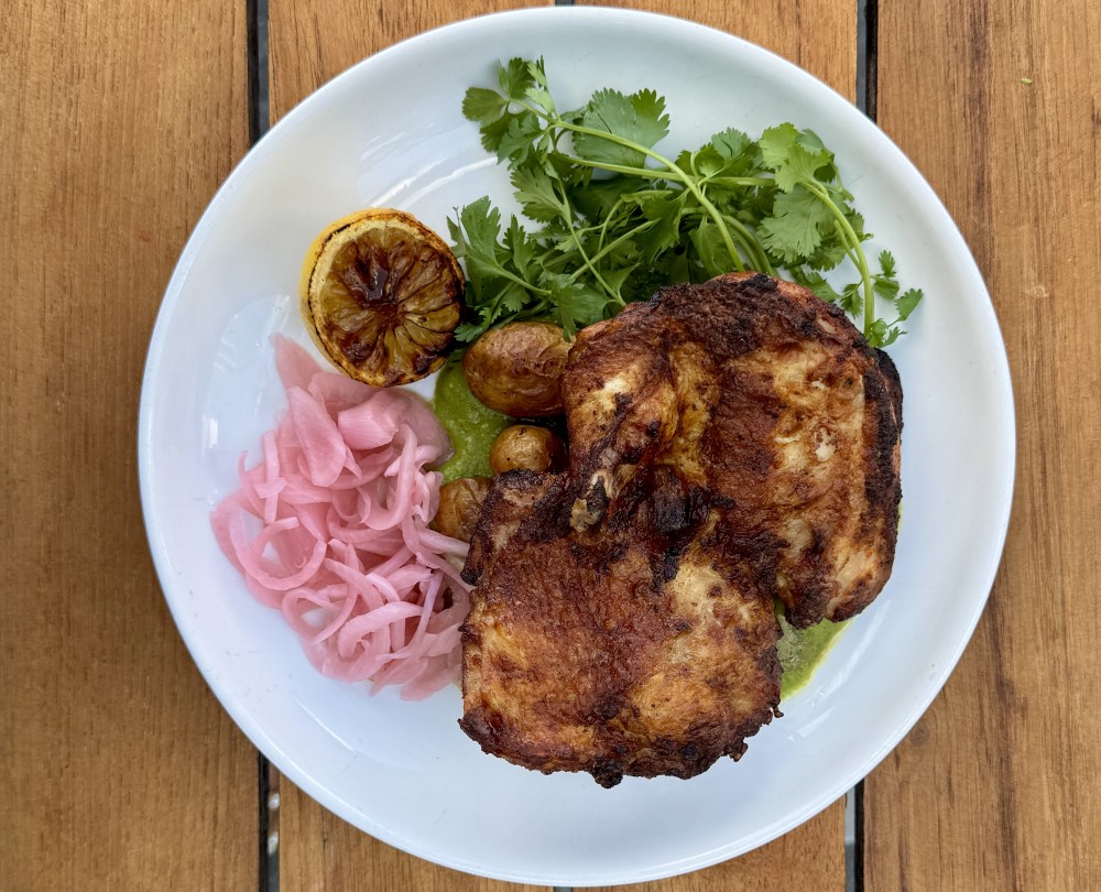 Half Chicken a la Brasa pan roasted with crispy skin  served with aji verde sauce crispy smashed potatoes, pickled onions & cilantro