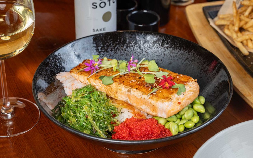 Fresh seared salmon poke, wakame, crab, avocado, edamame, tobiko, sushi rice, and a sweet chili Asian glaze—bursting with vibrant flavors!