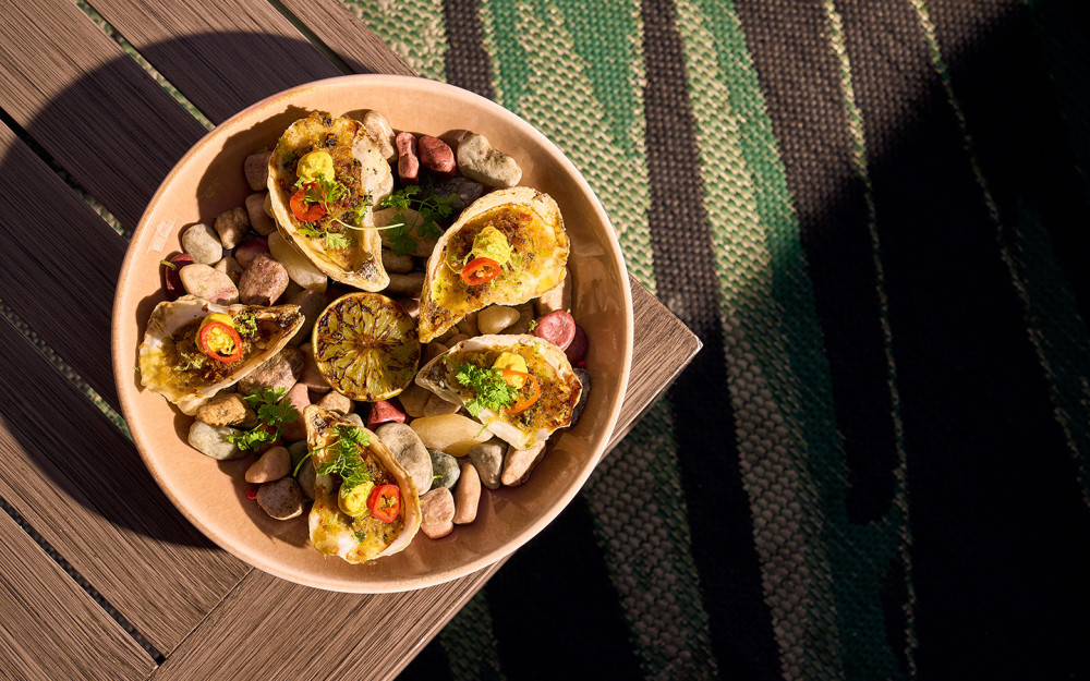 Oysters casino with Ají Amarillo Butter, Bacon Breadcrumbs, Pickled Fresno, and Pink Peppercorn Mignonette