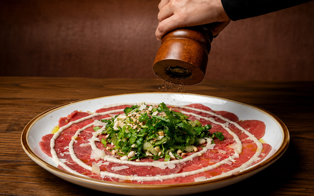 Thinly sliced beef carpaccio with arugula, mushrooms, and truffle dressing.