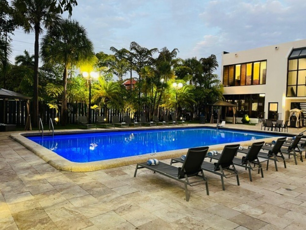 Escape to our tropical outdoor pool —lush palms, cozy loungers, and a serene vibe perfect for sunbathing, a peaceful retreat, or a refreshing swim.