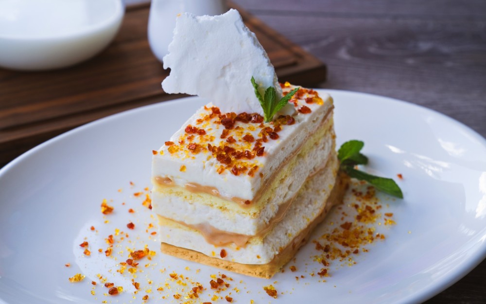 Soft layers of airy sponge cake filled with chirimoya manjar and chirimoya mousse, finished with caramel praline and crisp meringue shards
