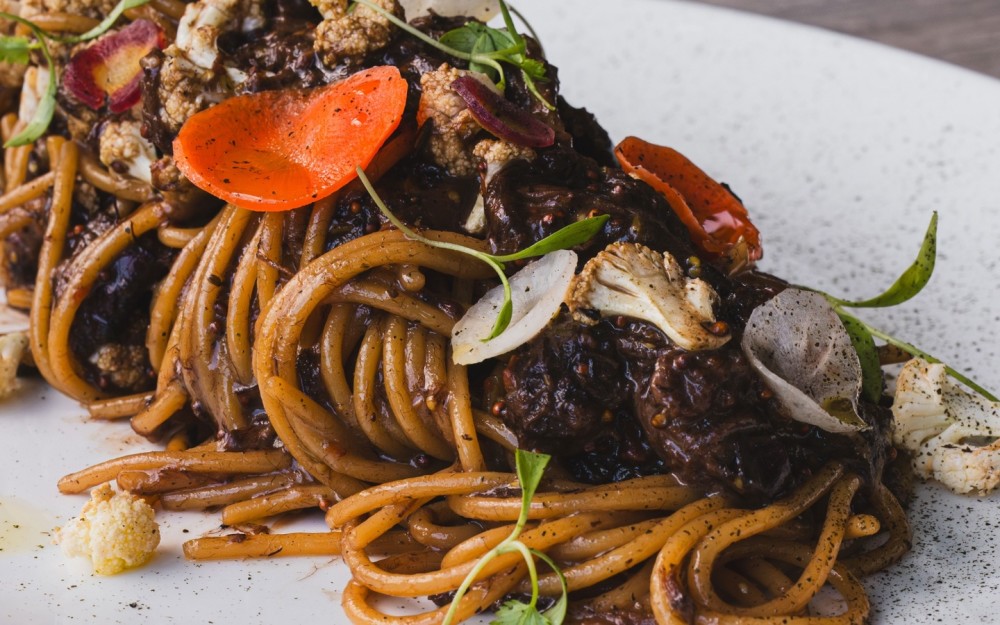 Spaghetti folded into a rich, slow-braised short rib ragú with red wine, ají panca and soy, finished with grain mustard, mushrooms, crispy vegetables