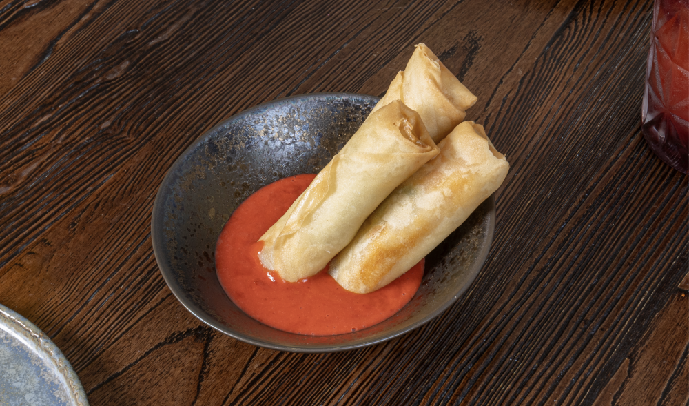 (1) One Shrimp Spring Roll Al Pastor with sweet red chilis and peanuts dipping sauce.