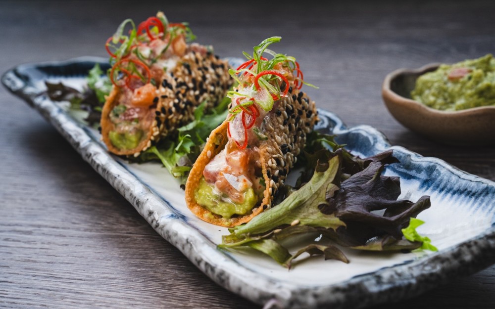 Crispy tacos with salmon & tuna tartare in acevichada sauce, “guacamole” and tobiko caviar (2 pcs)