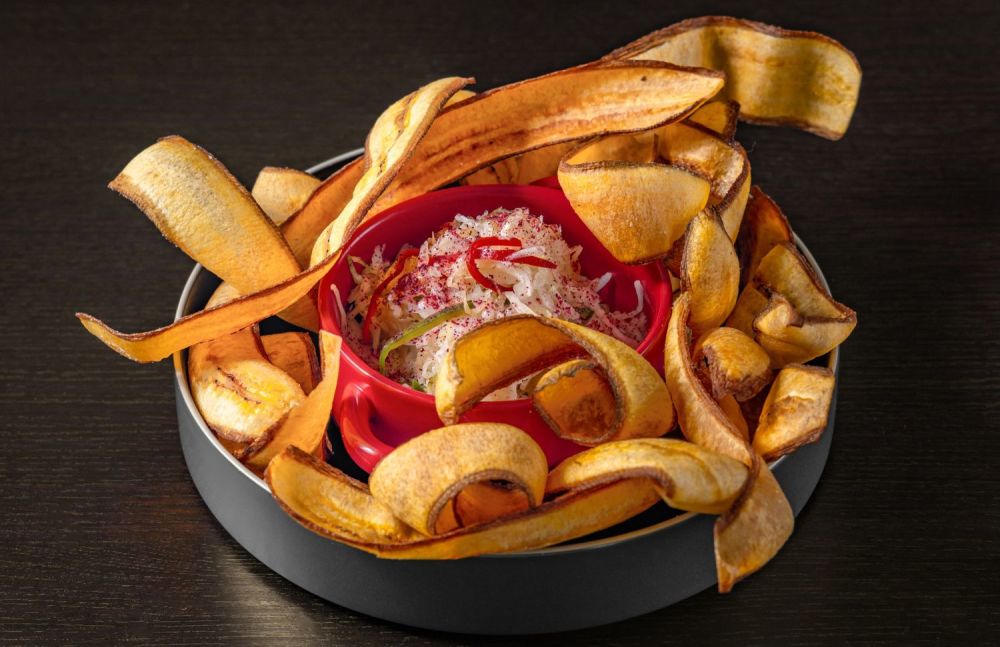 Fried green plantains served with pickled cabbage and hibiscus flowers