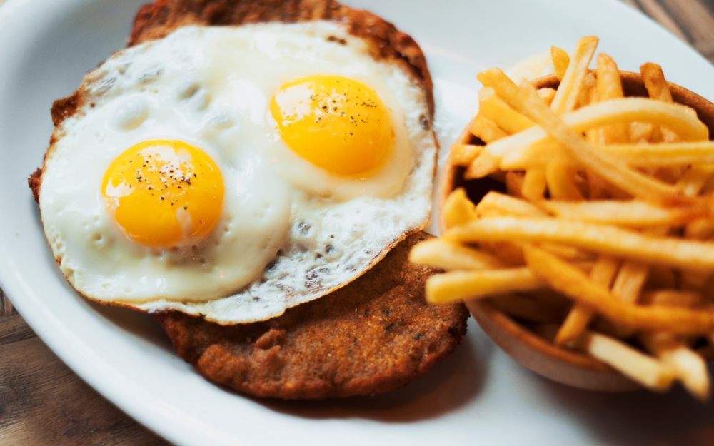 Veal Milanese topped with two eggs and french fries
