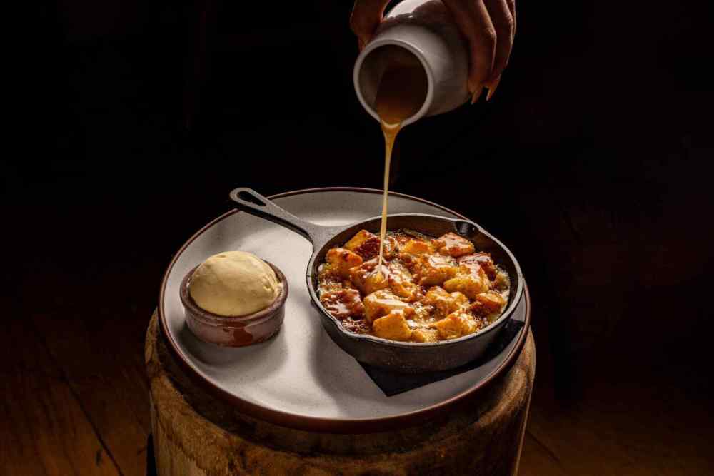 Warm comfort in every bite: Banana Fosters Bread Pudding with roasted white chocolate, butterscotch sauce & vanilla ice cream.