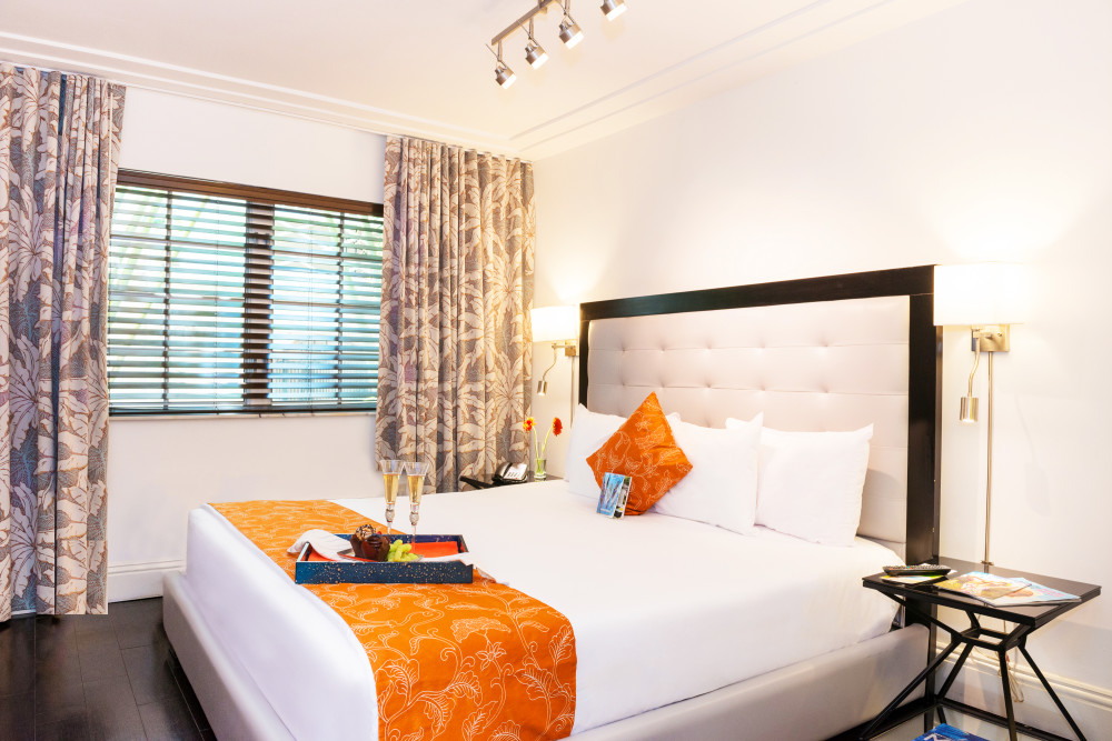 Riviera South Beach Hotel's Classic Room is furnished with a modern flare. A white, leather oversized bed frame sits above a Tempurpedic mattress, accompanied by all-white bedding, complete with 300 thread count sheets, and orange accents. An inviting, leather love-seat, creates a cozy sitting area, complete with an oriental inspired elephant end table. Rooms feature hardwood floors, as well two separate bathroom spaces, equipped with the newest stainless steel utilities. The room includes the most up-to-date entertainment system, complete with a wall-mounted 42-inch plasma TV with satellite service, an iPod docking station, in-room safe, and mini-refrigerator.