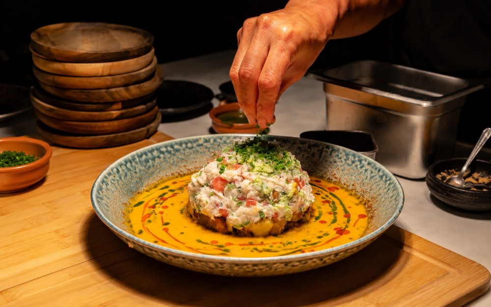 Inspired by a Sunday family meal. Blue crab prepared ceviche-style in a rich tomato base, served with cocolón, sweet plantains.
