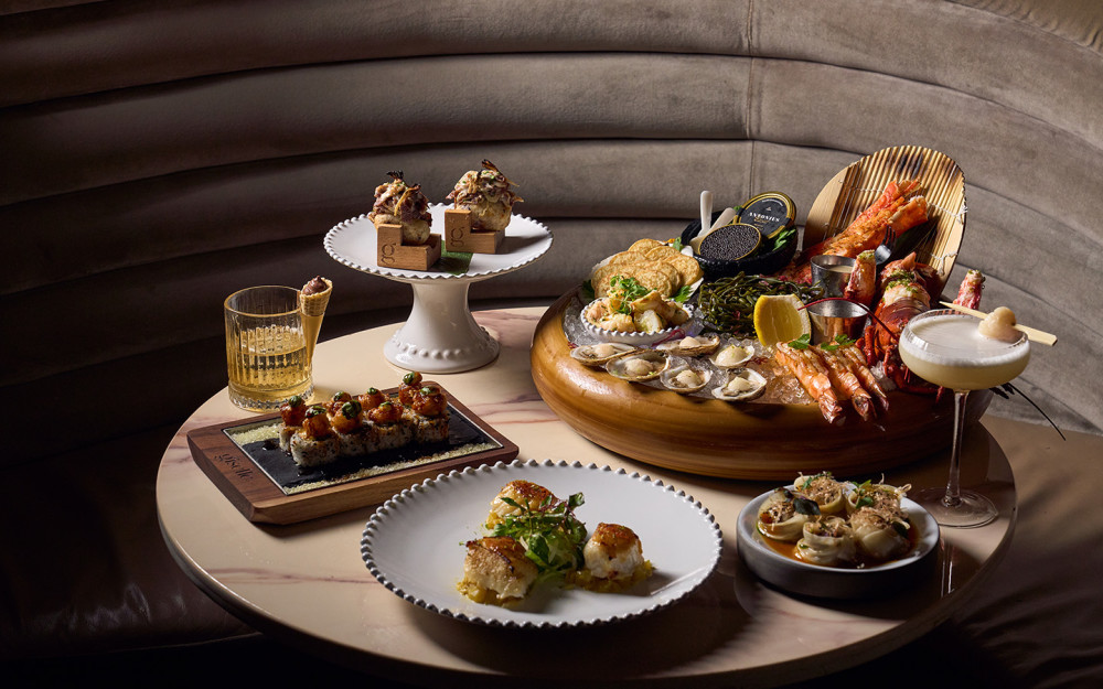 A selection of dishes featuring a seafood platter with caviar, sushi, and artfully plated bites, paired with signature cocktails