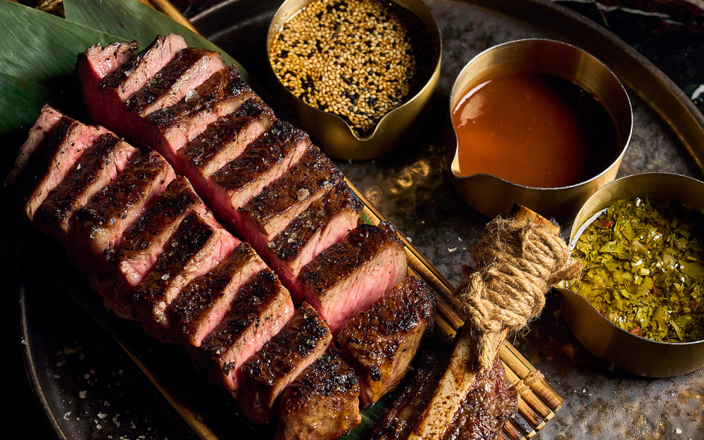 Sliced grilled steak served with a selection of savory sauces and seasonings