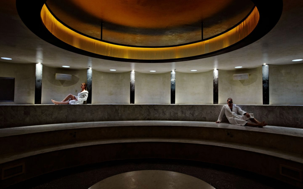 The Hamam at The Standard Spa offers a serene circular retreat with curved marble seating, warm lighting and a tranquil atmosphere.