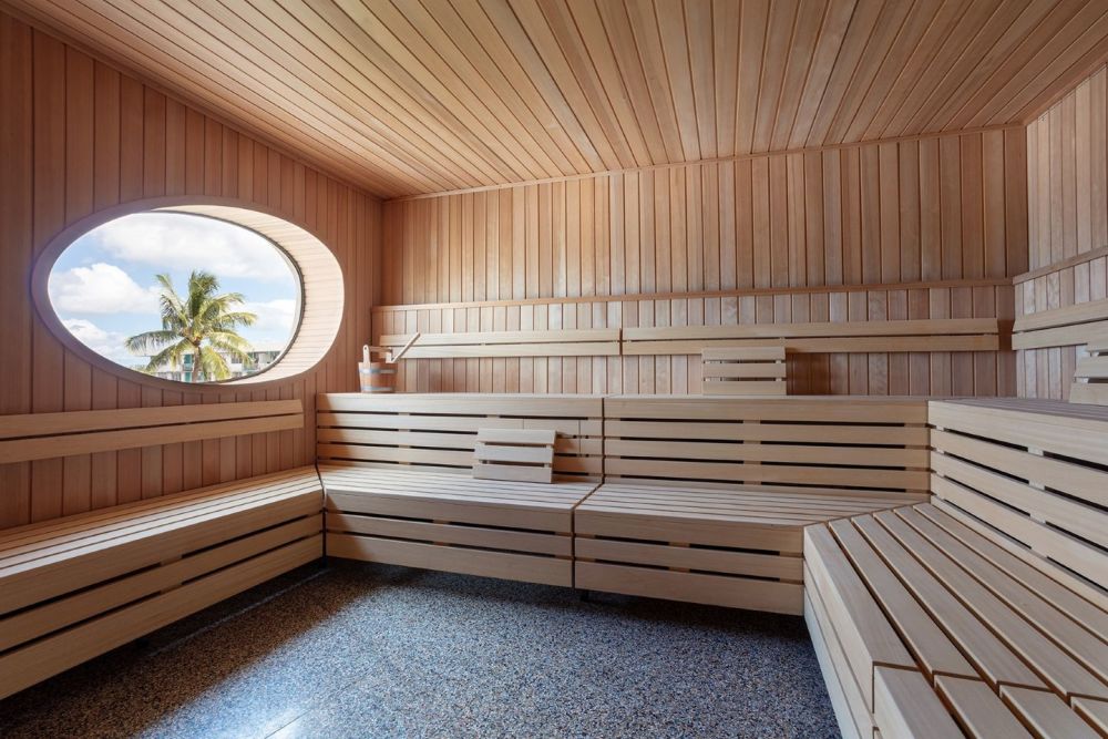 The Hemlock Sauna at The Standard Spa features warm wood interiors, tiered seating and a circular window overlooking Miami’s tropical landscape.