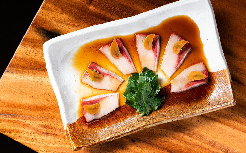 Thinly sliced yellowtail seabass with green chili relish + pickled garlic