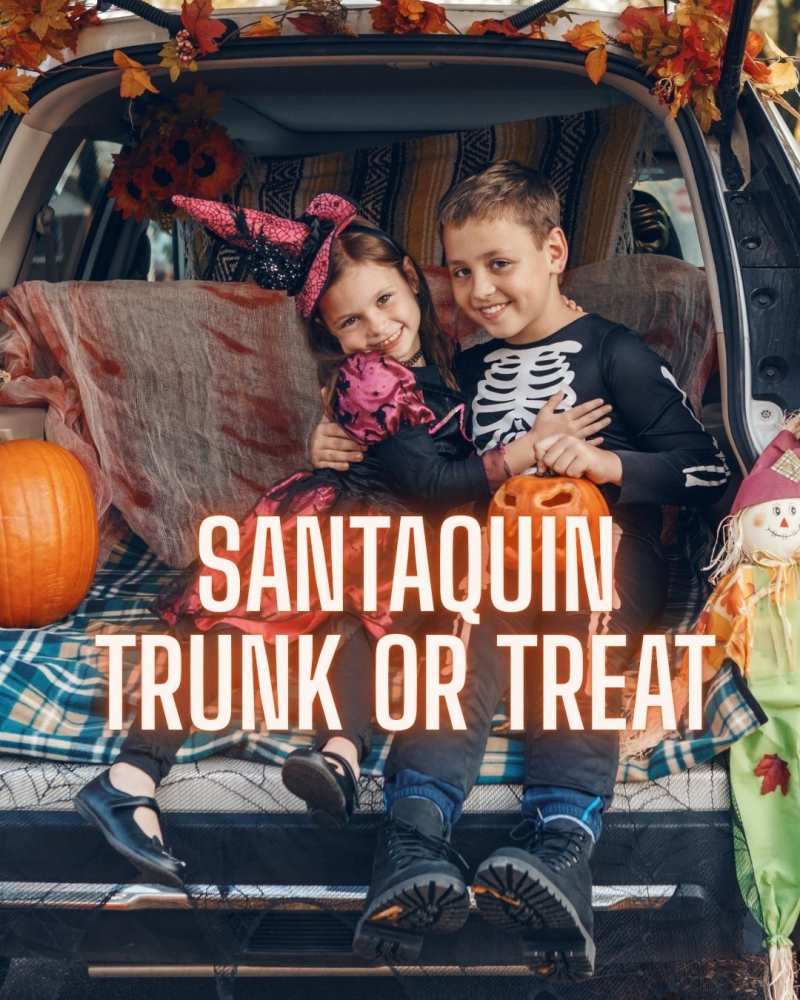 Two smiling kids in Halloween costumes sitting in a decorated car trunk, with the text Santaquin Trunk or Treat